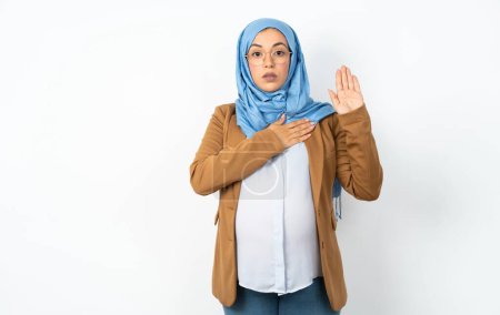 Téléchargez les photos : Femme enceinte musulmane portant hijab jurer avec la main sur la poitrine et la paume ouverte, faire un serment de fidélité - en image libre de droit