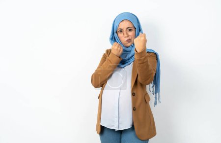 Téléchargez les photos : Femme enceinte musulmane portant hijab prêt à se battre avec geste de défense poing, visage en colère et bouleversé, peur du problème. - en image libre de droit