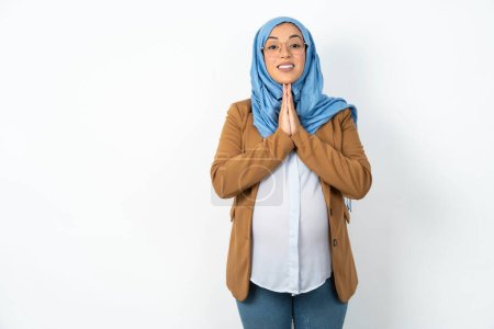Téléchargez les photos : Musulmane enceinte femme portant hijab prier avec les mains ensemble demander pardon souriant confiant. - en image libre de droit