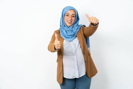 Téléchargez les photos : Femme enceinte musulmane portant hijab approuvant faire un geste positif avec la main, pouces levés souriant et heureux pour le succès. Le geste du gagnant. - en image libre de droit