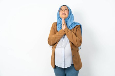 Téléchargez les photos : Femme enceinte musulmane portant hijab mendier et prier avec les mains ainsi que l'expression de l'espoir sur le visage très émotionnel et inquiet. Mon Dieu ! - en image libre de droit