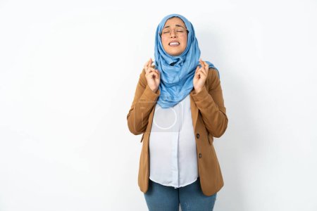 Photo for Pregnant muslim woman wearing hijab  gesturing finger crossed smiling with hope and eyes closed. Luck and superstitious concept. - Royalty Free Image