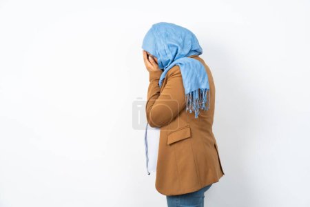 Photo for Sad beautiful pregnant muslim woman wearing hijab crying covering her face with her hands. - Royalty Free Image
