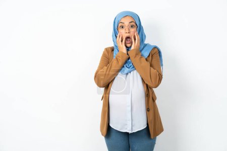 Foto de Asustado aterrorizado hermosa mujer musulmana embarazada usando hijab conmocionado con los precios en la tienda, la gente y el concepto de emociones humanas - Imagen libre de derechos