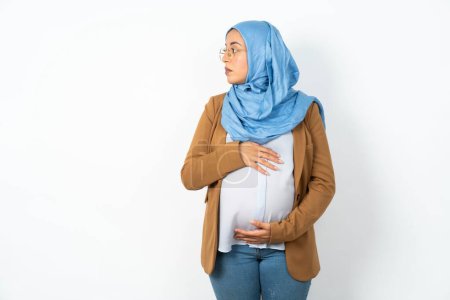 Téléchargez les photos : Belle femme musulmane enceinte portant hijab pas souriant écoute attentive concentrée - en image libre de droit