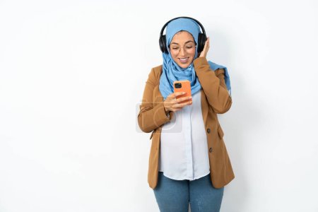 Téléchargez les photos : Heureuse belle femme musulmane enceinte portant hijab se sent bien tout en se concentrant sur l'écran du smartphone. Personnes, technologie, mode de vie - en image libre de droit