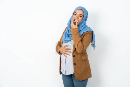Téléchargez les photos : Femme musulmane enceinte portant le hijab tenant un aligneur invisible prêt à l'utiliser. Concept de soins dentaires et de confiance. - en image libre de droit