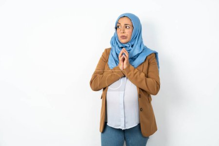 Photo for Beautiful pregnant muslim woman wearing hijab steepled fingers and looks mysterious aside has great evil plan in mind - Royalty Free Image