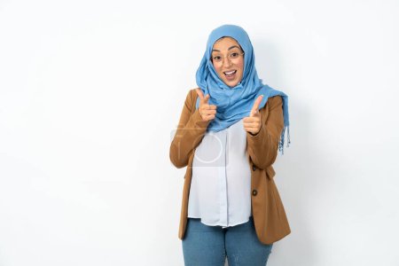 Foto de Hermosa mujer musulmana embarazada con hijab dirige los dedos a la cámara selecciona a alguien. Te recomiendo. La mejor opción - Imagen libre de derechos