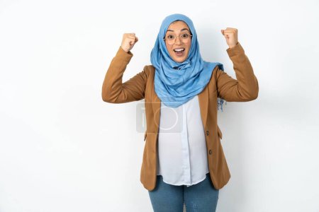 Téléchargez les photos : Choqué extatique belle femme musulmane enceinte portant hijab victoire chance loterie lever la main vers le haut crier oui - en image libre de droit