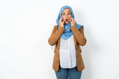 Photo for Speechless beautiful pregnant muslim woman wearing hijab  keeps hands near opened mouth reacts to shocking news stares wondered at camera - Royalty Free Image