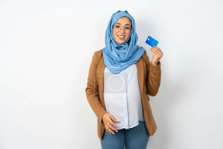 Photo for Photo of happy cheerful smiling beautiful pregnant muslim woman wearing hijab recommend credit card - Royalty Free Image