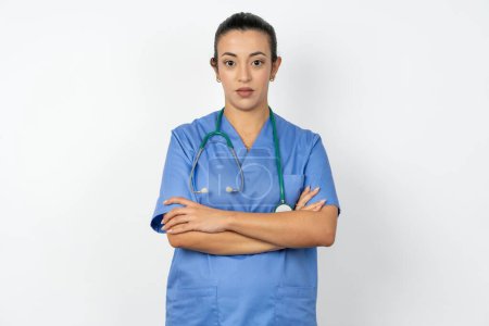 Photo for Serious pensive arab doctor woman wearing blue uniform feel like cool confident entrepreneur cross hands. - Royalty Free Image