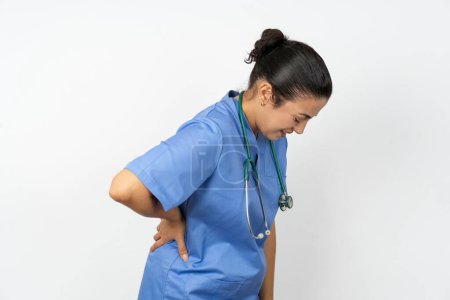 Téléchargez les photos : Médecin arabe femme portant l'uniforme bleu Souffrant de maux de dos, toucher le dos avec la main, douleur musculaire - en image libre de droit