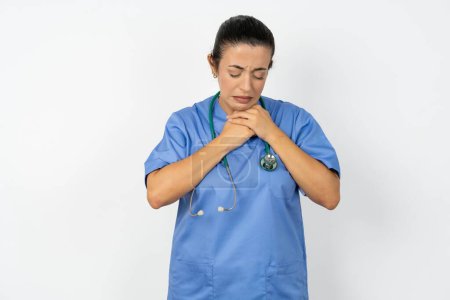 Foto de Mujer médica árabe triste vistiendo uniforme azul desesperada y deprimida con lágrimas en los ojos sufriendo dolor y depresión en la tristeza expresión facial y concepto de emoción - Imagen libre de derechos