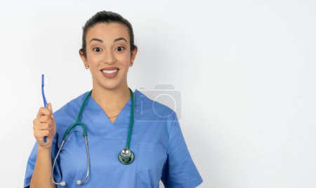 Foto de Mujer árabe médico en uniforme con estetoscopio sosteniendo un cepillo de dientes y sonriendo. Concepto de salud dental. - Imagen libre de derechos