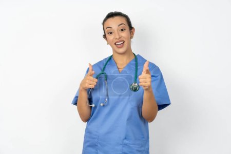 Foto de Mujer árabe médico en uniforme con estetoscopio dirige los dedos a la cámara selecciona a alguien. Te recomiendo. La mejor opción - Imagen libre de derechos