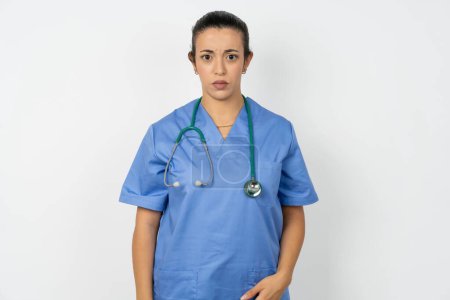 Photo for Displeased arab doctor woman wearing blue uniform frowns face feels unhappy has some problems. Negative emotions and feelings concept - Royalty Free Image