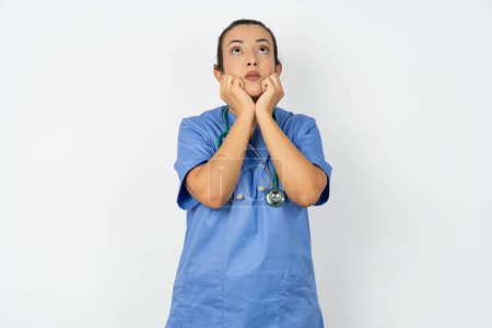 Foto de Retrato de triste árabe médico mujer usando azul uniforme manos cara mirada espacio vacío - Imagen libre de derechos