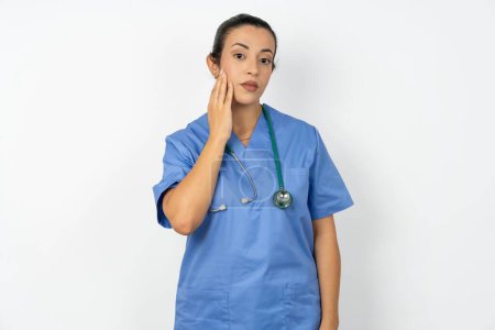 Téléchargez les photos : Photo de médecin arabe femme portant l'uniforme bleu profiter fraîche peau lisse toucher visage - en image libre de droit