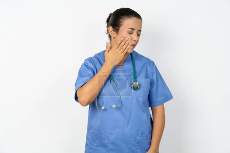 Foto de Árabe médico mujer vistiendo uniforme azul con dolor de muelas sobre fondo blanco - Imagen libre de derechos