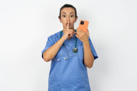 Photo for Arab doctor woman wearing blue uniform holding modern gadget ask not tell secrets - Royalty Free Image