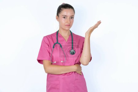 Téléchargez les photos : Studio shot of frustrated caucasian female doctor gesturing with raised palm, frowning, being displeased and confused with dumb question. - en image libre de droit