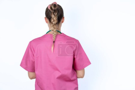 Foto de Médico femenino caucásico de pie hacia atrás mirando hacia otro lado con los brazos en el cuerpo. - Imagen libre de derechos