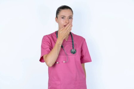 Photo for Sleepy caucasian female doctor  yawning with messy hair, feeling tired after sleepless night, yawning, covering mouth with palm. - Royalty Free Image