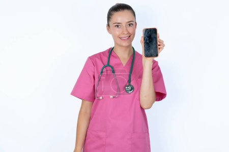 Téléchargez les photos : Médecin caucasien souriant montrant écran de téléphone vide. Concept de publicité et de communication. - en image libre de droit