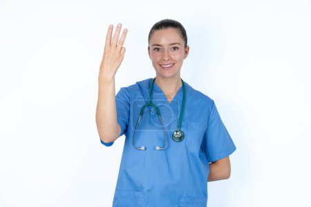 Photo for Caucasian female doctor smiling and looking friendly, showing number three or third with hand forward, counting down - Royalty Free Image