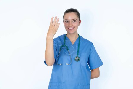 Photo for Caucasian female doctor smiling and looking friendly, showing number four or fourth with hand forward, counting down - Royalty Free Image