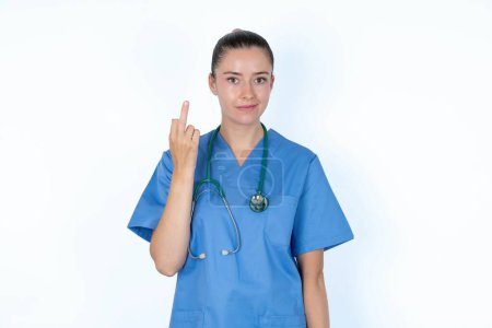 Photo for Caucasian female doctor shows middle finger bad sign asks not to bother. Provocation and rude attitude. - Royalty Free Image