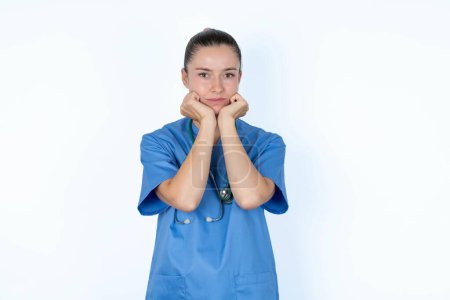 Foto de Retrato de mujer triste caucásica médico en uniforme con estetoscopio con las manos cerca de la cara - Imagen libre de derechos