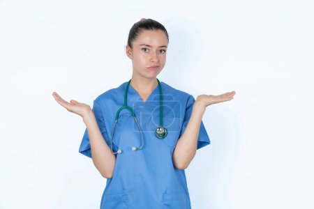 Téléchargez les photos : Insouciante jolie femme caucasienne médecin en uniforme avec stéthoscope haussant les épaules, oups. - en image libre de droit
