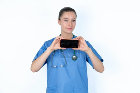 Téléchargez les photos : Femme caucasienne médecin en uniforme avec stéthoscope tenant dans les mains téléphone - en image libre de droit