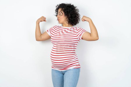 Téléchargez les photos : Femme enceinte montrant les muscles des bras souriant fier. Concept de fitness. - en image libre de droit