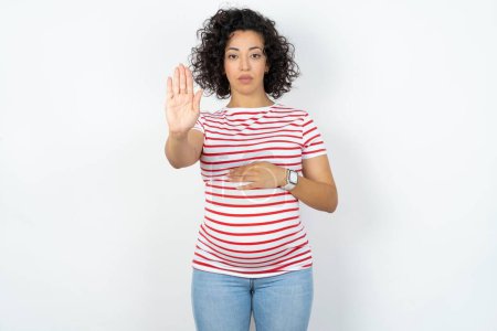 Photo for Pregnant woman doing stop sing with palm of the hand. Warning expression with negative and serious gesture on the face. - Royalty Free Image