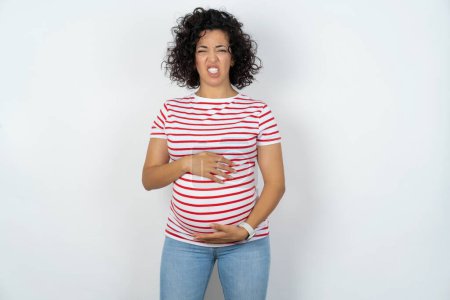 Photo for Pregnant woman keeps teeth clenched, frowns face in dissatisfaction, irritated because of much duties. - Royalty Free Image