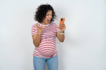 Foto de Mujer embarazada enojada gritando por teléfono, discutiendo con un empleado. Problemas en el trabajo. - Imagen libre de derechos