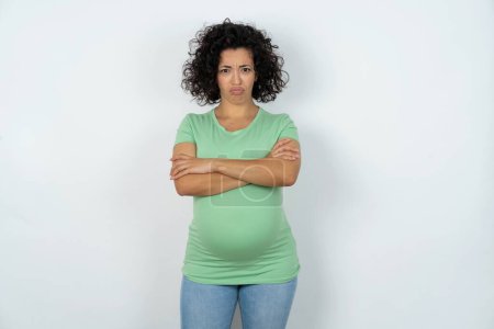 Photo for Gloomy dissatisfied pregnant woman looks with miserable expression at camera from under forehead, makes unhappy grimace - Royalty Free Image