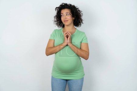Photo for Pregnant woman steepled fingers and looks mysterious aside has great evil plan in mind - Royalty Free Image