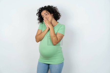 Overjoyed pregnant woman laughs joyfully and keeps palms pressed together hears something funny