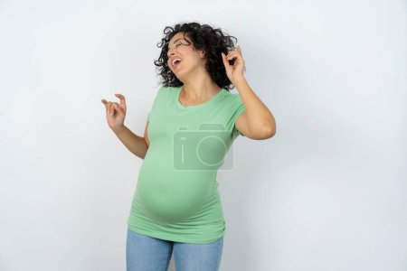 Photo for Photo of upbeat pregnant woman has fun and dances carefree wear being in perfect mood makes movements. Spends free time on disco party - Royalty Free Image
