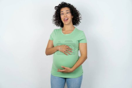 Photo for Funny pregnant woman makes grimace and crosses eyes plays fool has fun alone sticks out tongue. - Royalty Free Image