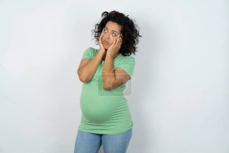 Foto de Mujer embarazada mantiene las manos en las mejillas ha aburrido expresión disgustado. Modelo sin esperanza estresado - Imagen libre de derechos
