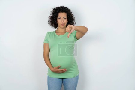 Photo for Pregnant woman looking unhappy and angry showing rejection and negative with thumbs down gesture. Bad expression. - Royalty Free Image