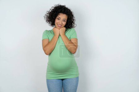 Téléchargez les photos : Satisfait femme enceinte touche menton avec les deux mains, sourit agréablement, se réjouit bonne journée avec amant - en image libre de droit