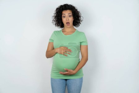Photo for Shocked pregnant woman stares with bugged eyes and keeps mouth opened with surprised expression. Omg concept - Royalty Free Image