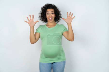 Téléchargez les photos : Délicieuse femme enceinte positive ouvre la bouche et les bras avec ses paumes vers le haut après avoir obtenu un excellent résultat - en image libre de droit